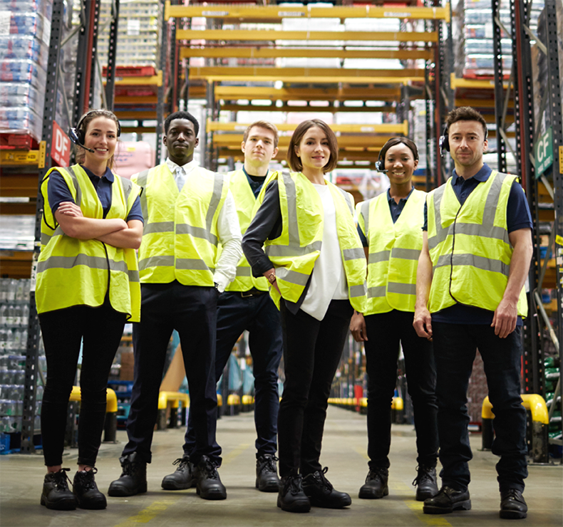 Team of happy warehouse workers posing, representing a transformed workforce empowered by Elevate labour management system for logistics.