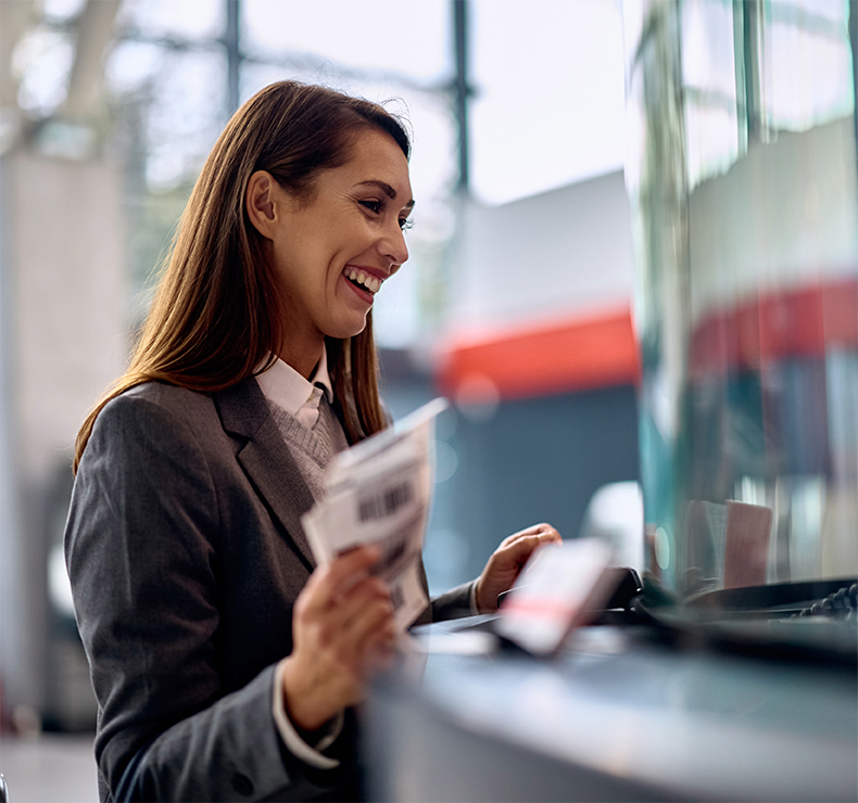 Happy customer at train station ticket booth, representing improved service through transformed rail workforce management.