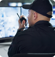 Enhanced Security Operations with Elevate Security officer reviewing camera footage and talking on walkie-talkie, representing enhanced operations and compliance with Elevate workforce management.